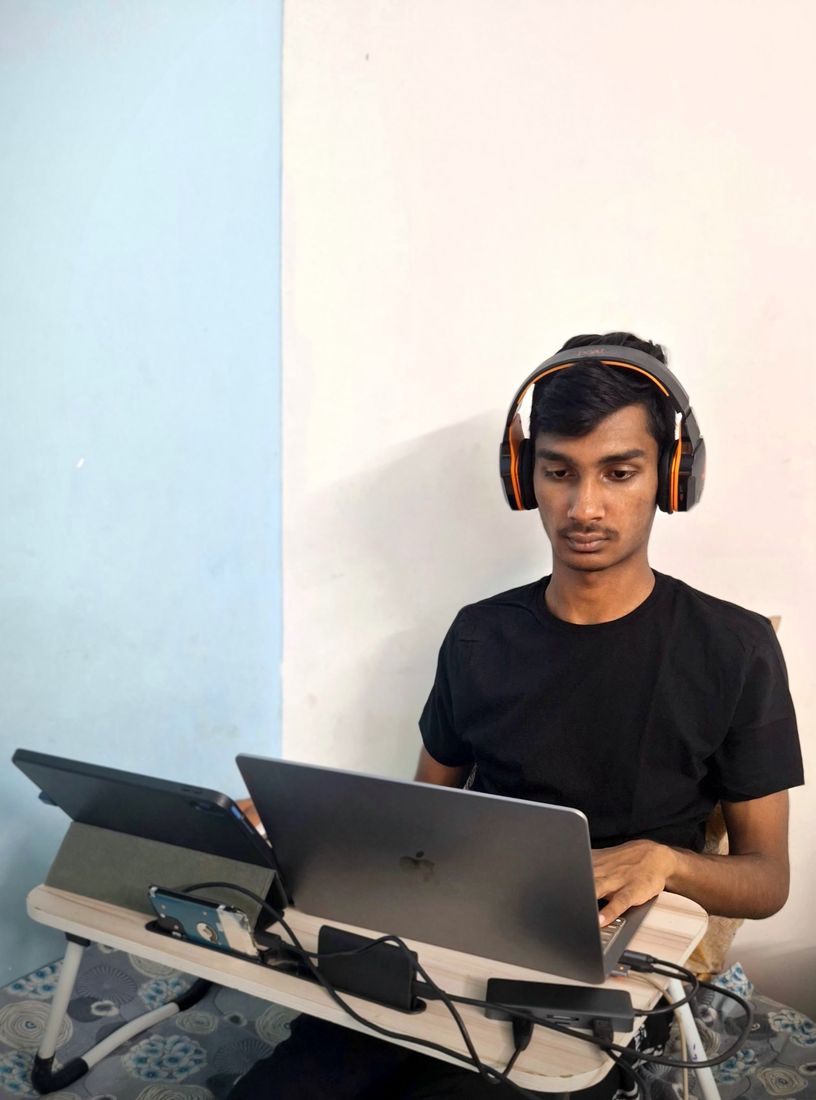 Nuthan at his desk with headphones, laptop and tablet
