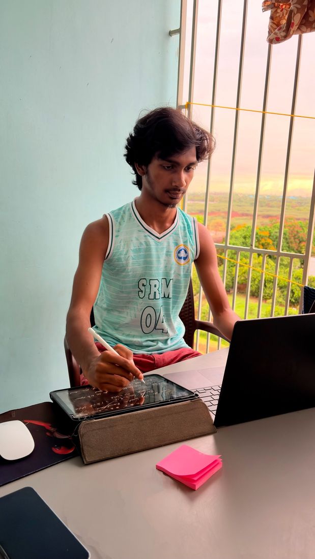 Nuthan in an SRM jersey writing notes on a tablet next to his laptop