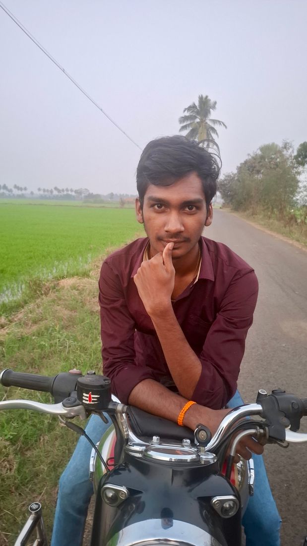 Nuthan on a motorbike beside green paddy fields
