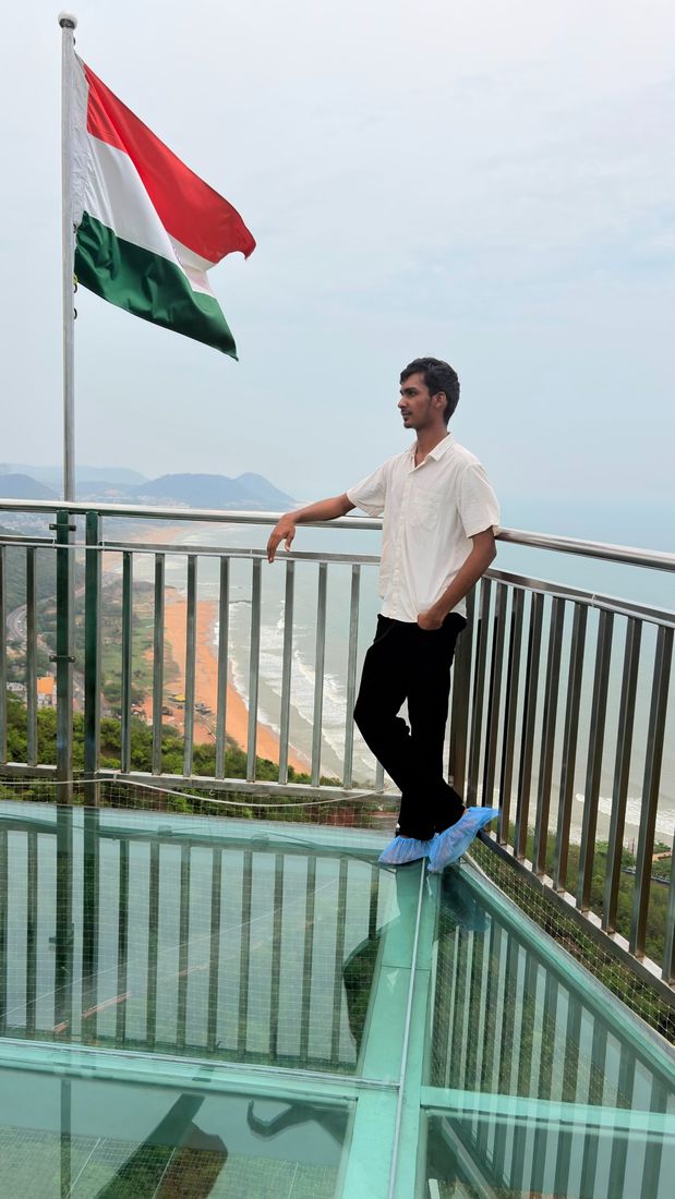 Nuthan on a glass skywalk beside the Indian flag